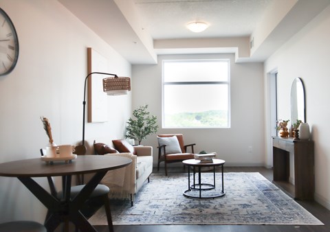 A living room with a couch, a table, and a clock on the wall.