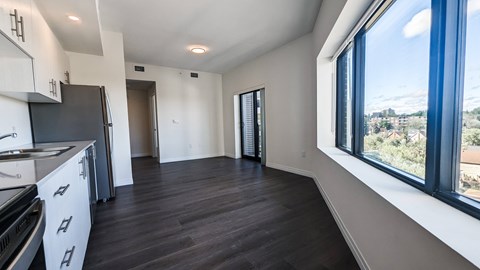 A kitchen with white cabinets and a black fridge is shown.