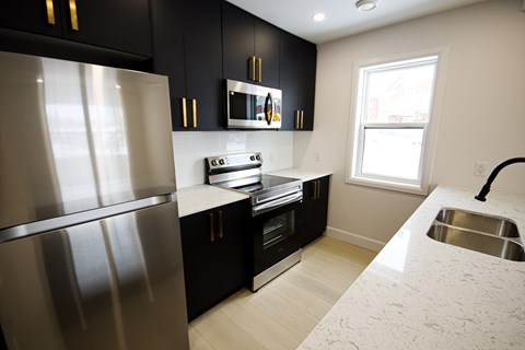 A modern kitchen with black cabinets and stainless steel appliances.