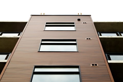 A tall building with a brown facade and multiple windows.