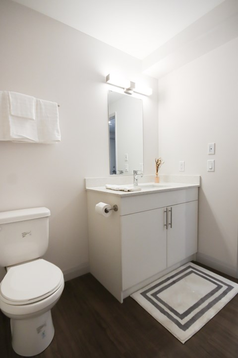 A white toilet sits next to a white sink in a small bathroom.