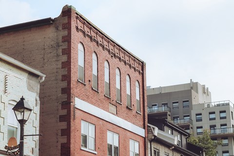 A red brick building with white trim and windows sits next to a white building with a black lamp post.