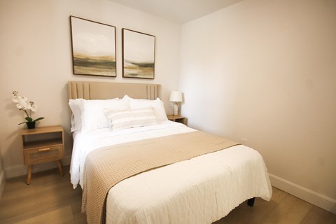 A bedroom with a large bed and two framed pictures on the wall.