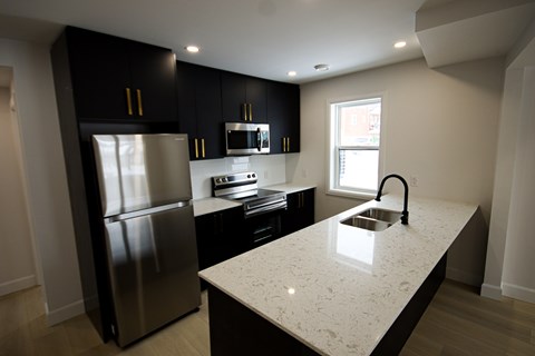 A kitchen with a stainless steel refrigerator and a granite countertop.
