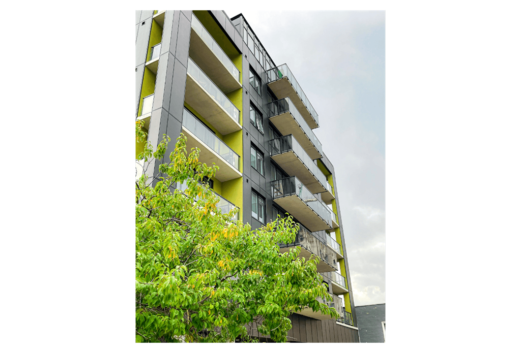 A modern building with balconies and trees in front.