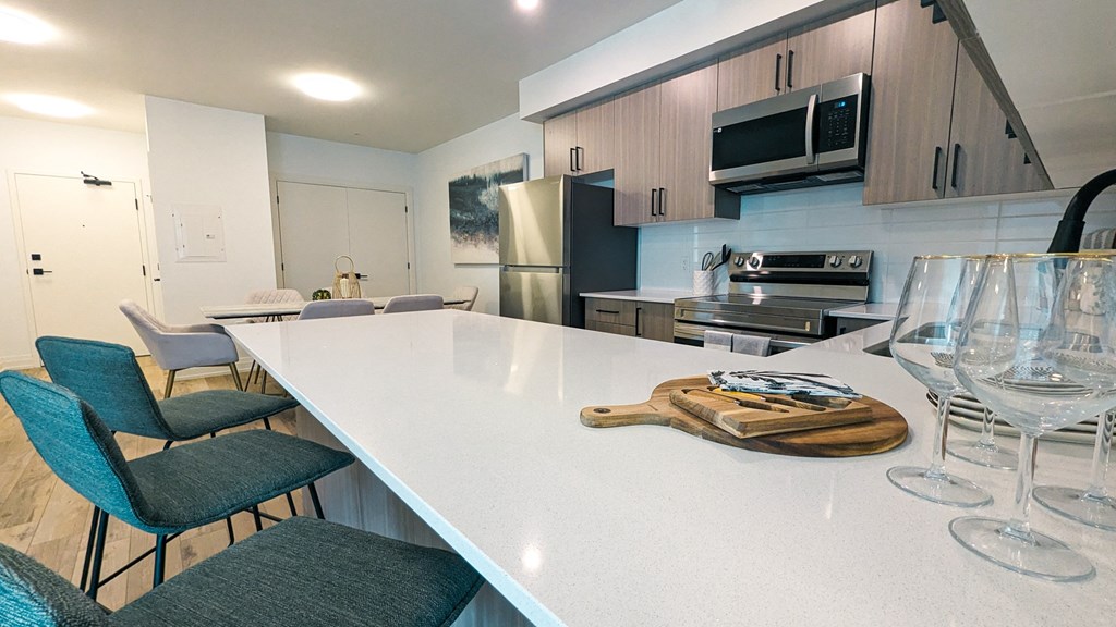 a kitchen with a white counter top and an island with wine glasses