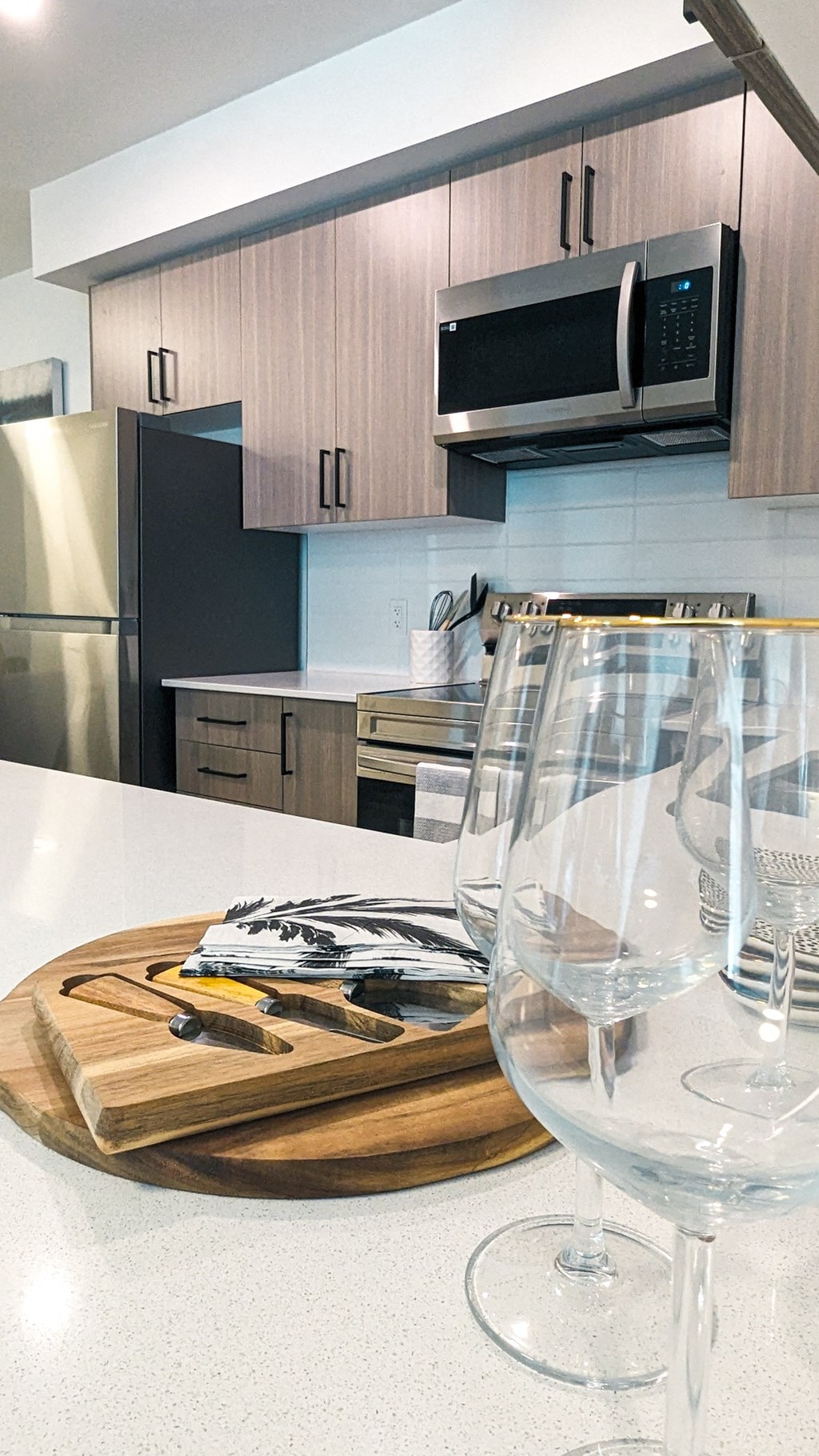 a kitchen with wine glasses and a cutting board on a counter