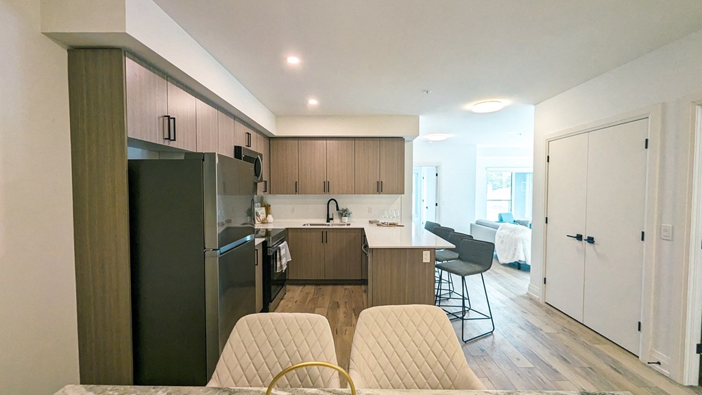 a kitchen and living room with wood flooring and a stainless steel refrigerator