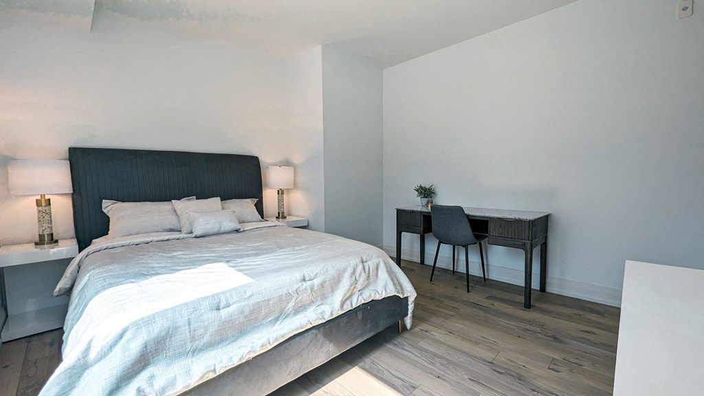 a bedroom with a large bed and a desk with a chair