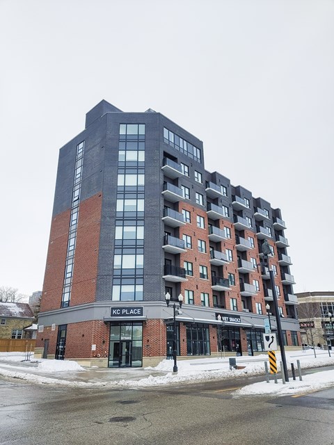 A tall building with a red brick base and a black top with the words KC PLACE on it.