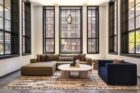 A living room with a large rug and a coffee table in front of a large window.