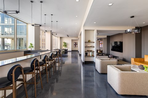 A modern living room with a long row of chairs and a bar area.