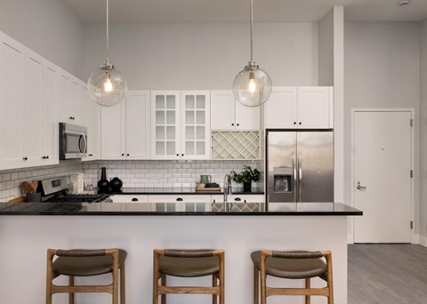 A kitchen with white cabinets and a black countertop.