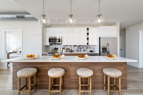 A kitchen with a white countertop and bar stools.