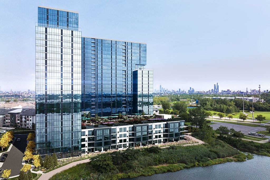 Exterior photo of RVR showing the building on the water, the dramatic 5th floor outdoor recreation area, with the New York City skyline in the background.