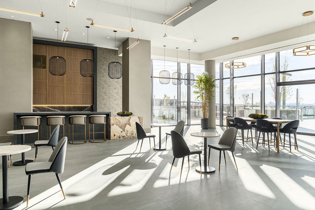 Interior photo of the club room showing multiple seating areas, dramatic lighting, large tile flooring and huge floor to ceiling windows.