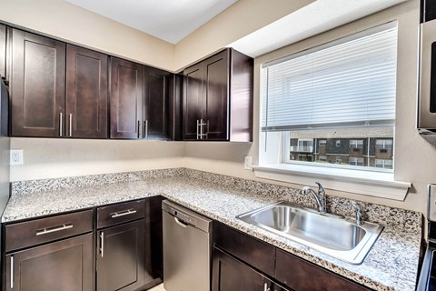 A kitchen with brown cabinets and a stainless steel dishwasher and oven.