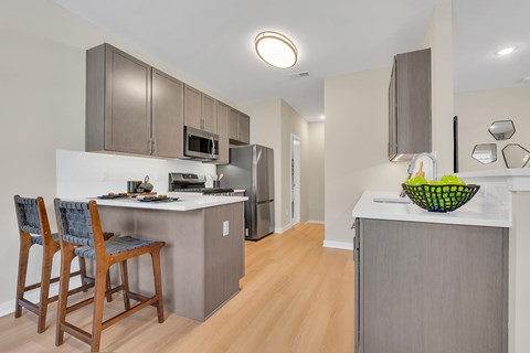 A kitchen with a white counter top and wooden floors.