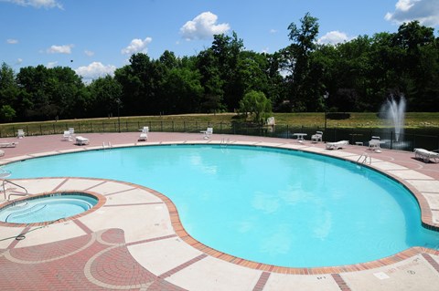 Pike Run Village Pool photo showing the pool and several chairs and tables surrounded by a fence. There are several trees that highlight the landscape.