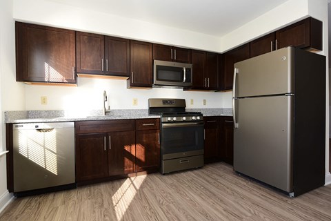 A kitchen with a refrigerator, oven, and microwave.