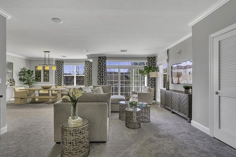 A living room with a grey sofa and a vase of flowers on a table.