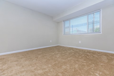 an empty living room with a window and carpet
