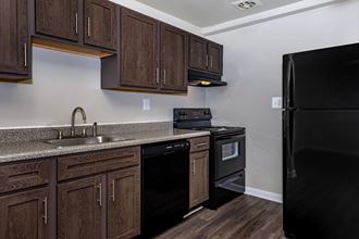 a kitchen with brown cabinets and black appliances at Highland Ridge, Capitol Heights, MD