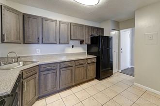 a kitchen with wooden cabinets and a black refrigerator at Waterford Tower, Silver Spring, 20904