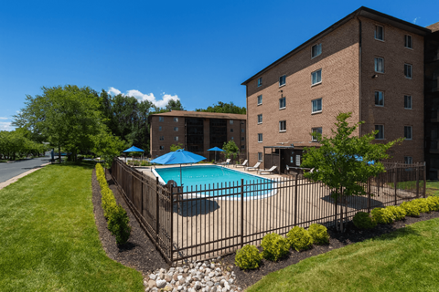 A pool surrounded by a black fence and green bushes.