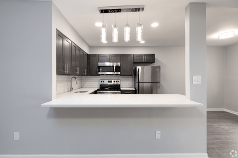 A modern kitchen with a white countertop and black cabinets.
