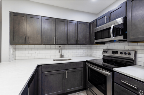 A kitchen with black cabinets and white countertops.