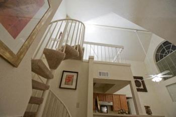 a spiral staircase in a house with a kitchen in the background