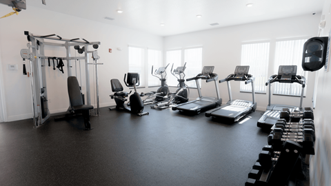 A gym with a variety of equipment including treadmills, weights, and exercise machines.