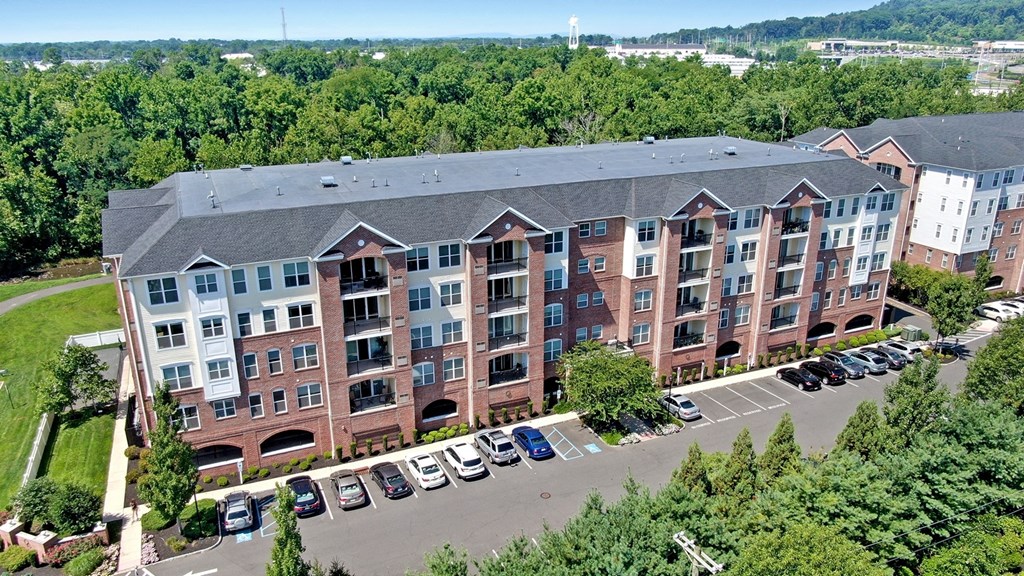 A large red brick apartment building with a parking lot in front.