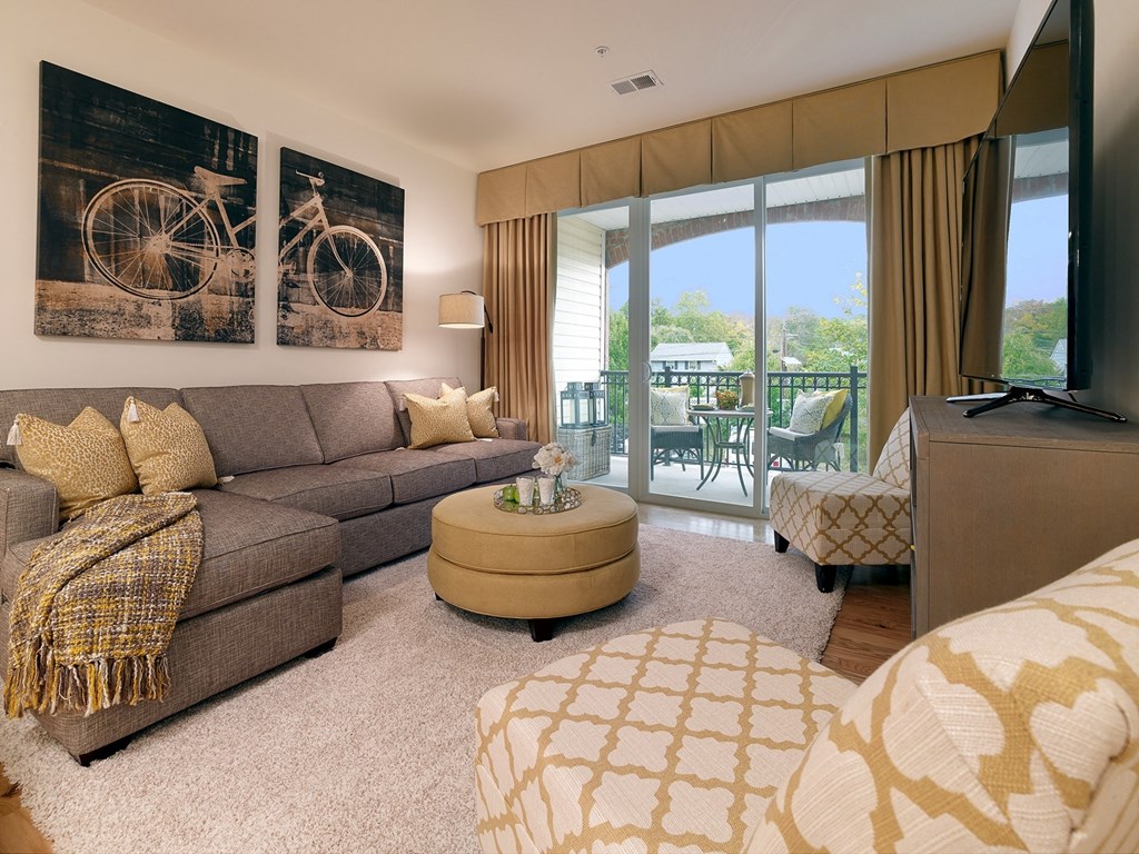 a living room with a couch and a tv and a balcony