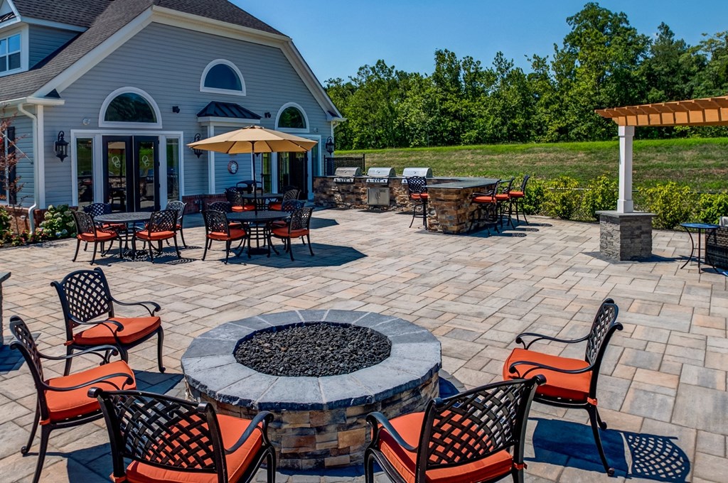 A patio with a fire pit and chairs.