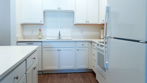 A white kitchen with a refrigerator on the right.