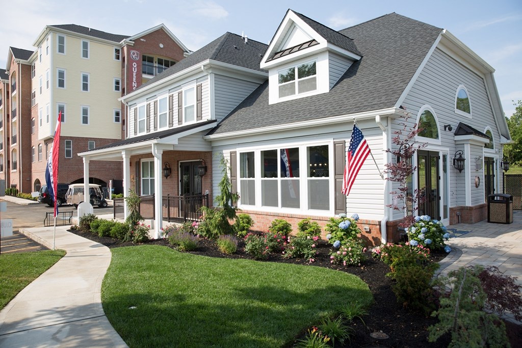 A white house with a grey roof and a flag on the front porch.