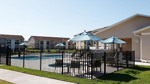 A black fence surrounds a pool area with umbrellas.