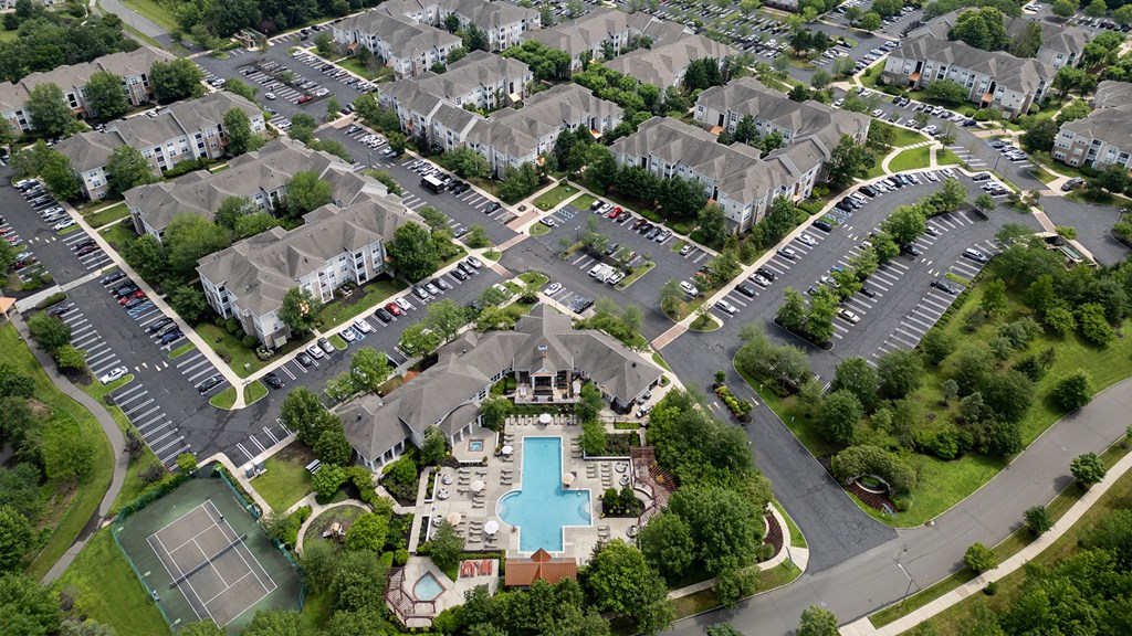 A bird's eye view of a residential complex with a swimming pool and tennis court.