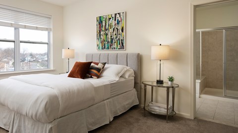 A bedroom with a large bed and a painting on the wall.