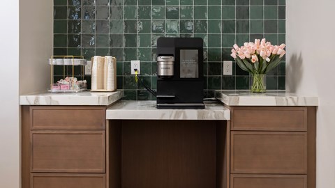 A kitchen counter with a vase of flowers and a coffee maker.