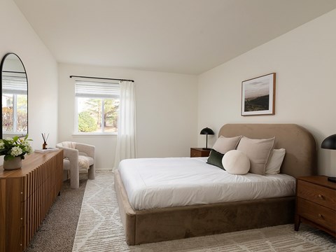 A bedroom with a large bed and a window with blinds.