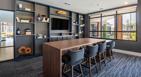 A modern dining room with a long table and grey chairs.