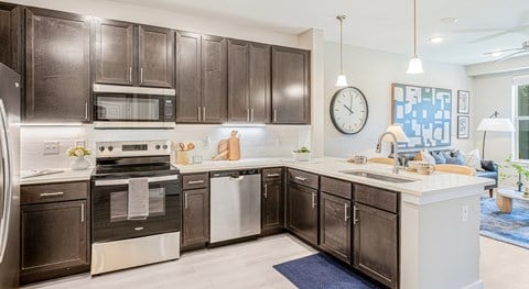 A modern kitchen with dark brown cabinets and stainless steel appliances.