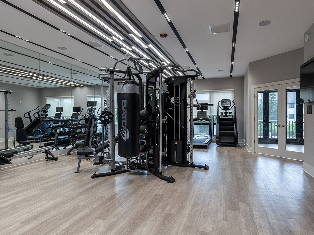 a gym with cardio machines and weights on a wooden floor