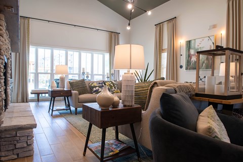 A living room with a grey couch and a table with a vase on it.