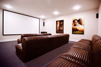 a home theater room with a projector screen and leather couches