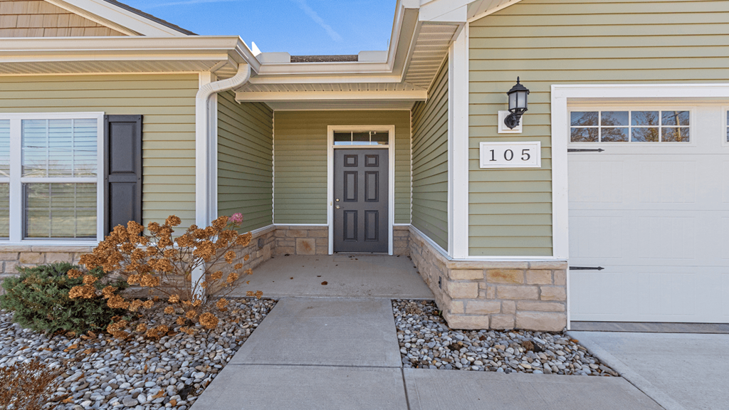 a front door of a home with a walkway and a driveway