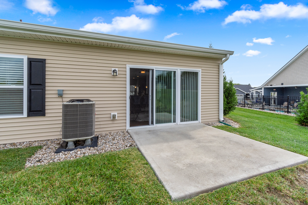 the entrance to a tan house with a patio and a backdoor